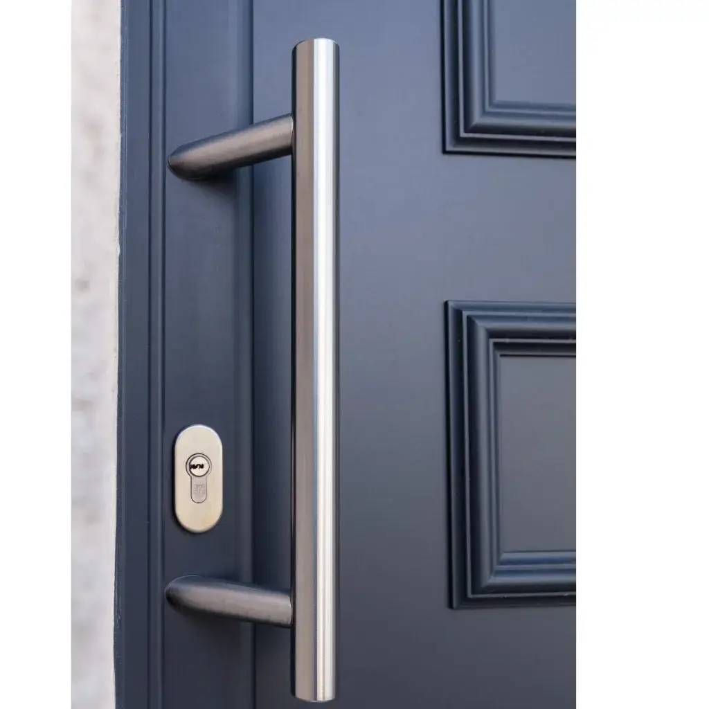 Une poignée de porte moderne en acier inoxydable est fixée sur une porte bleue élégante avec moulures.