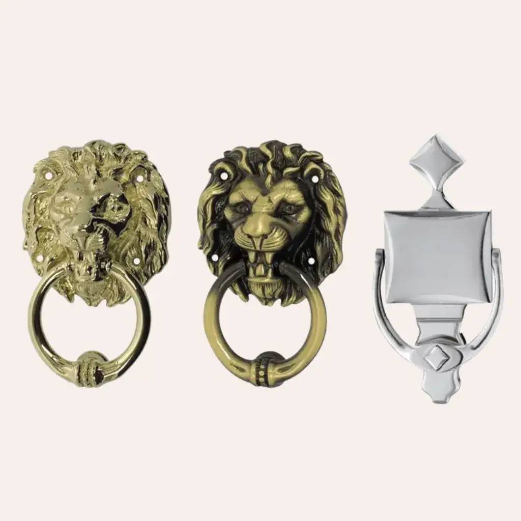 Trois heurtoirs de porte en métal décoratifs sont alignés, avec deux en forme de têtes de lion et un au design géométr