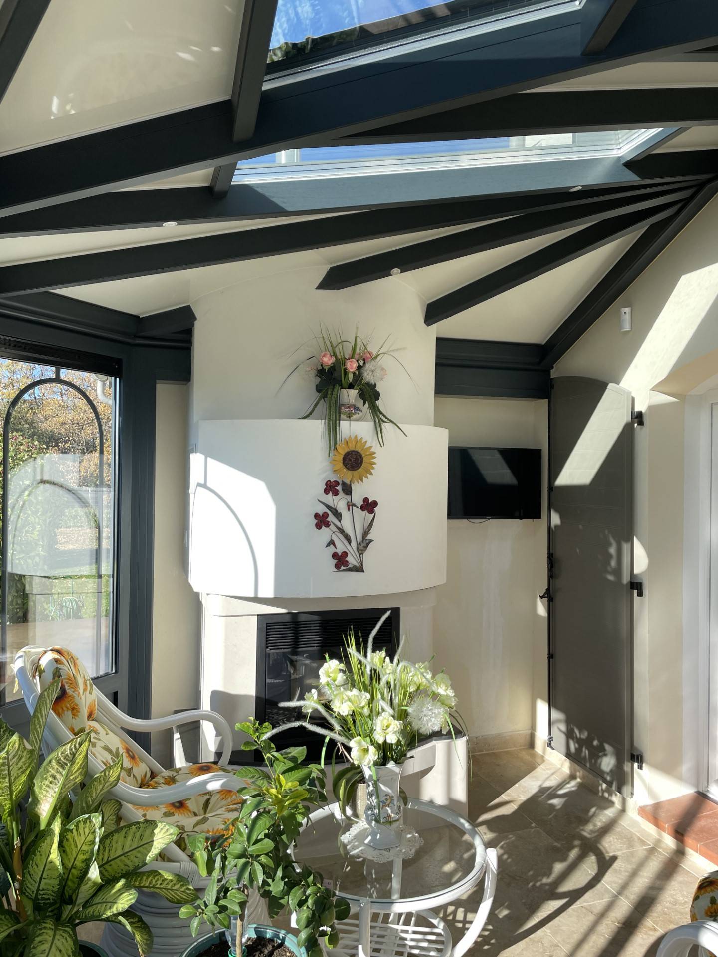 Véranda lumineuse avec cheminée et décorations florales naturelles