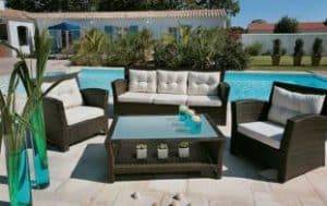 Ensemble de meubles de jardin en rotin autour d'une piscine.