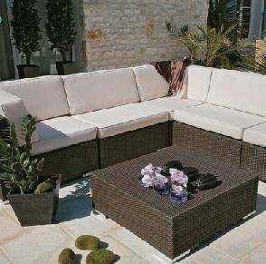 Canapé d'extérieur en rotin sous une pergola moderne entourée de plantes