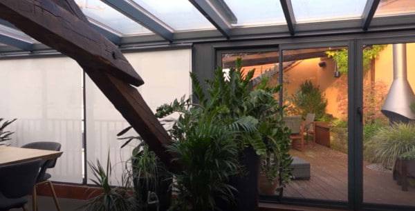 Véranda moderne avec toit vitré et décoration intérieure végétalisée