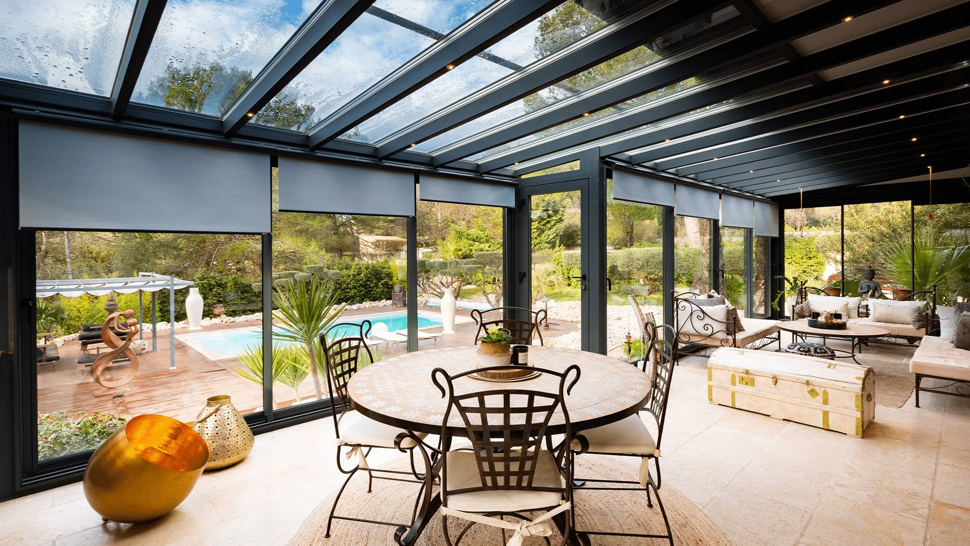 Grand salon véranda avec stores et toit vitré