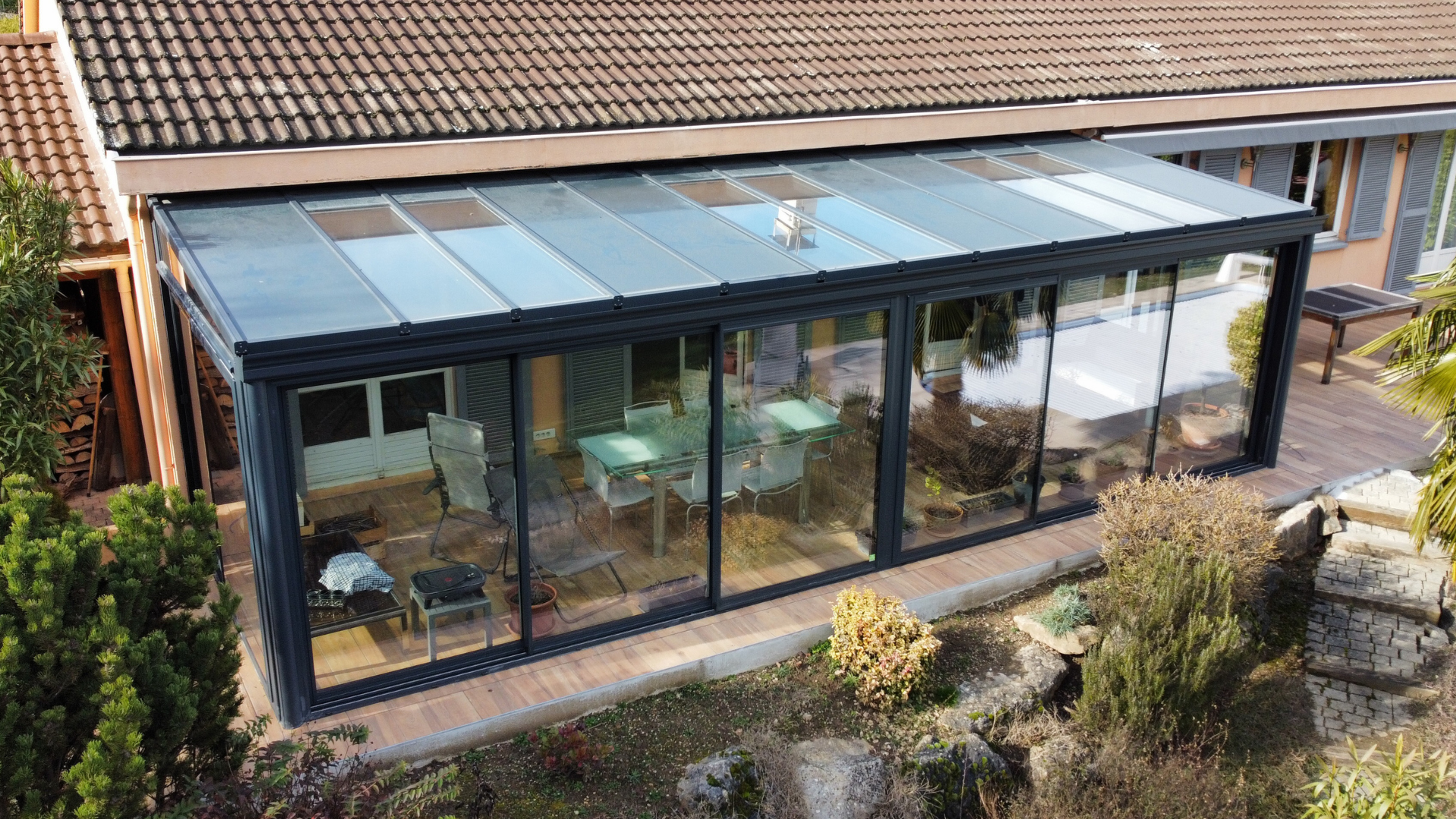 Véranda en verre moderne adossée à une maison avec jardin