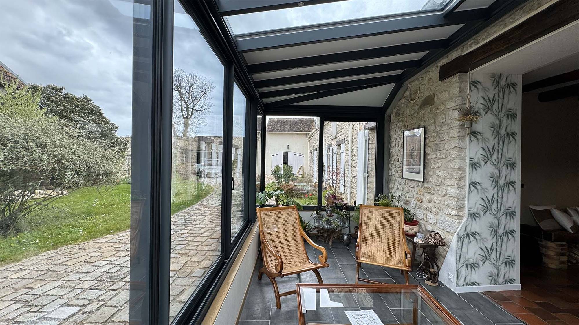 Véranda moderne avec grandes baies vitrées et espace détente lumineux