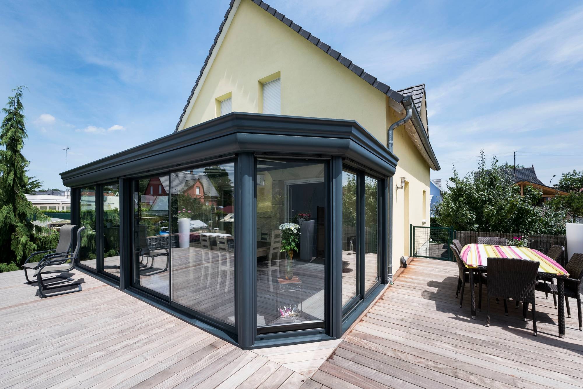 Véranda moderne en aluminium avec terrasse en bois accueillante