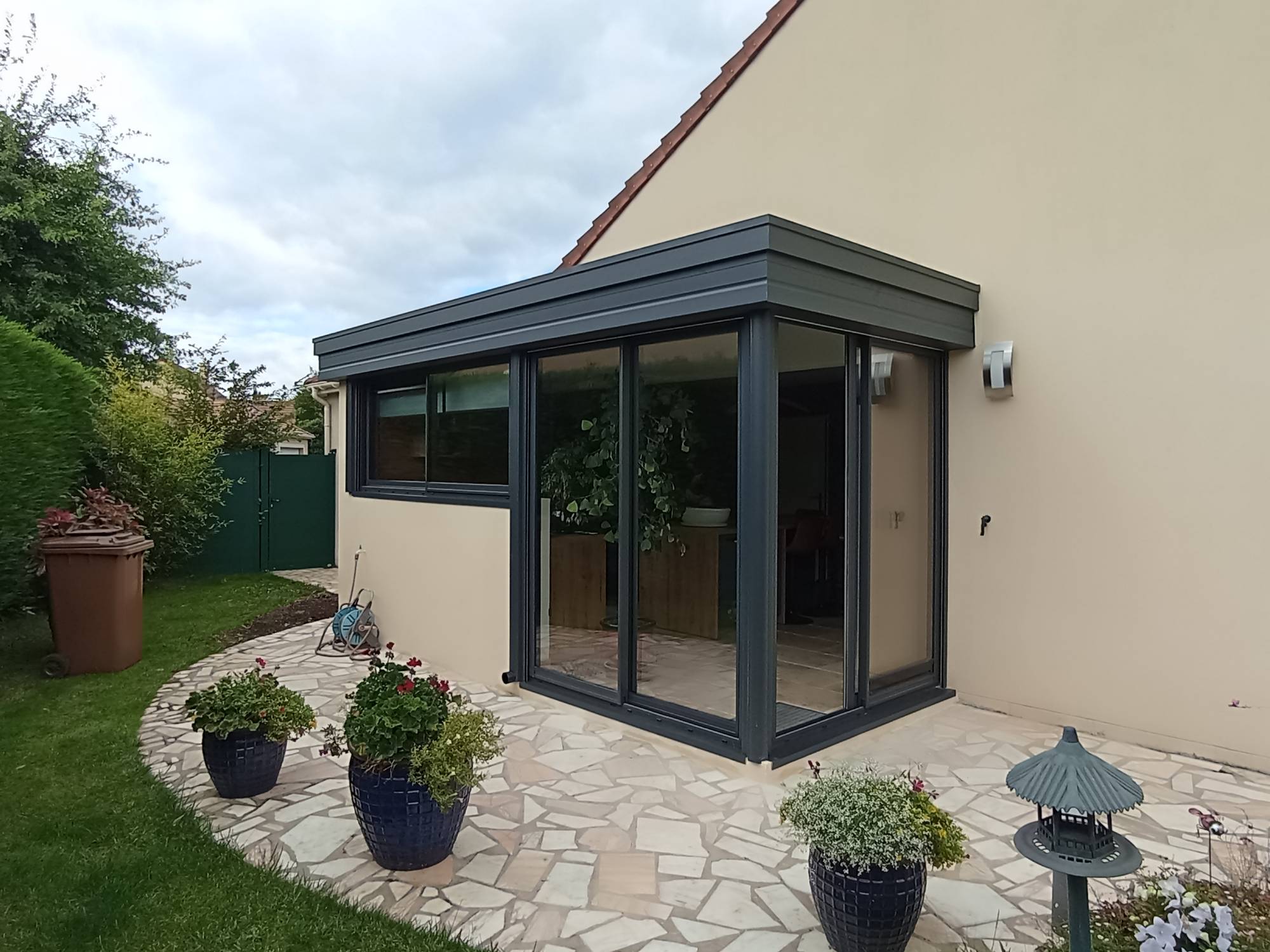 Véranda moderne en aluminium attenante à une maison avec jardin