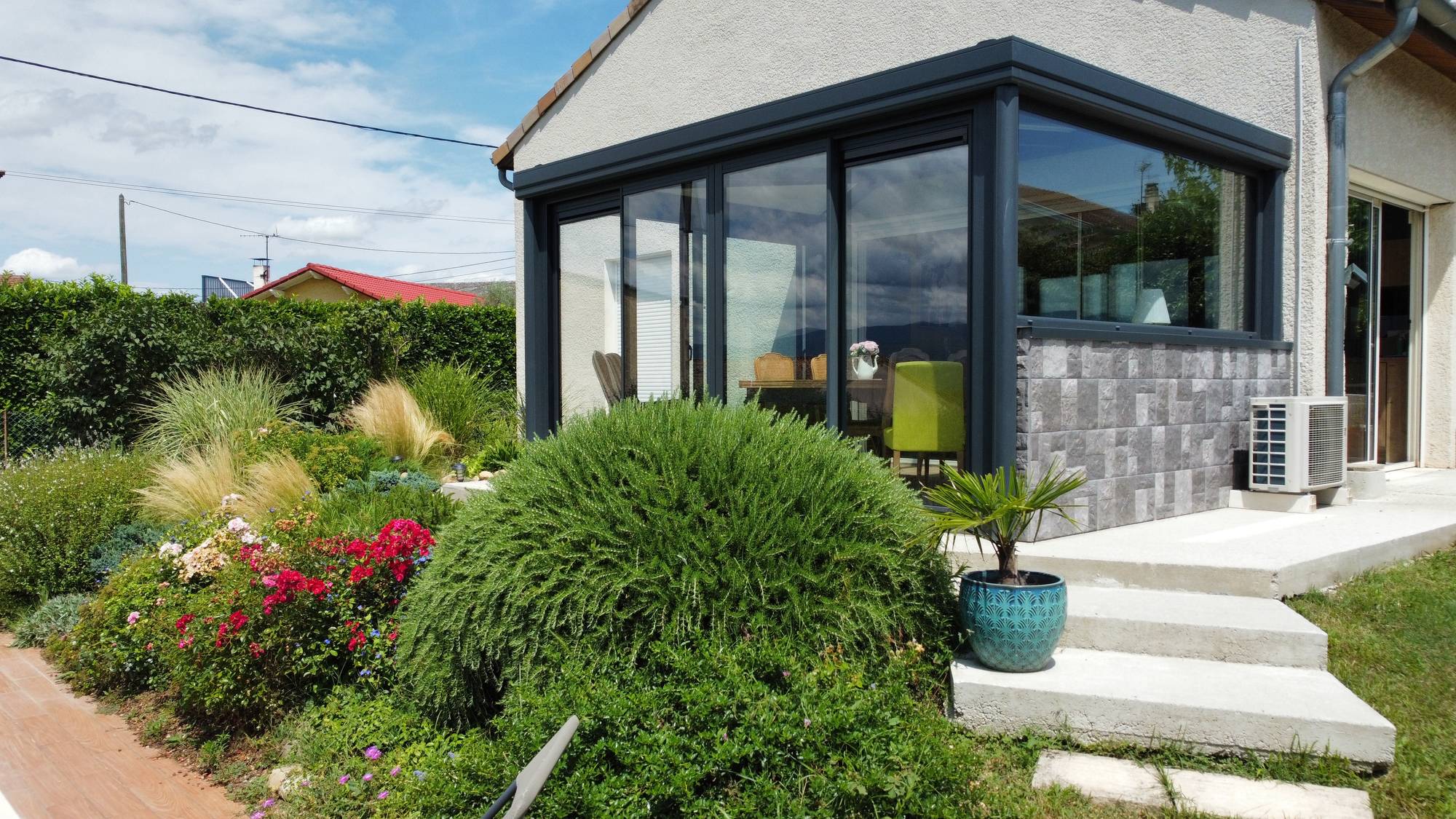 Véranda moderne avec grandes fenêtres dans un jardin fleuri