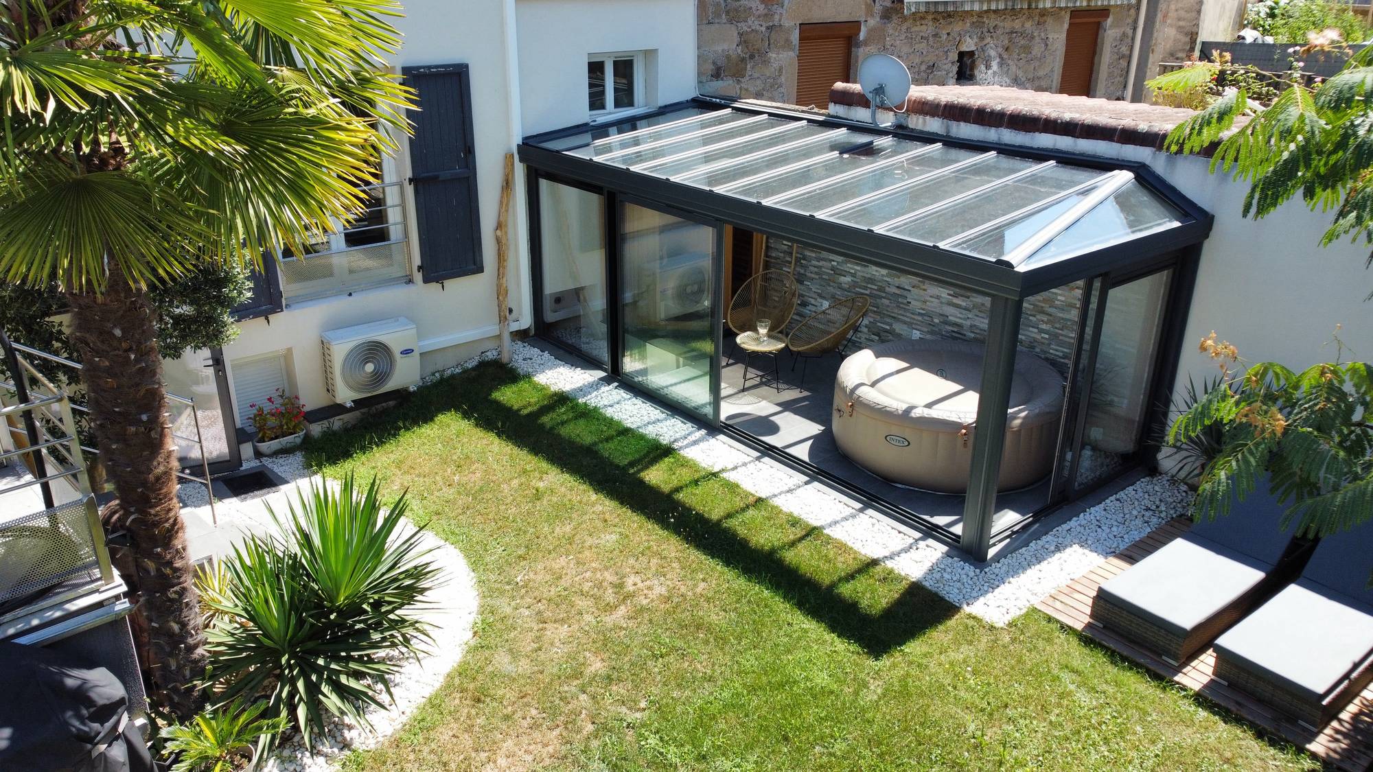 Véranda moderne avec portes vitrées et toit en verre transparent