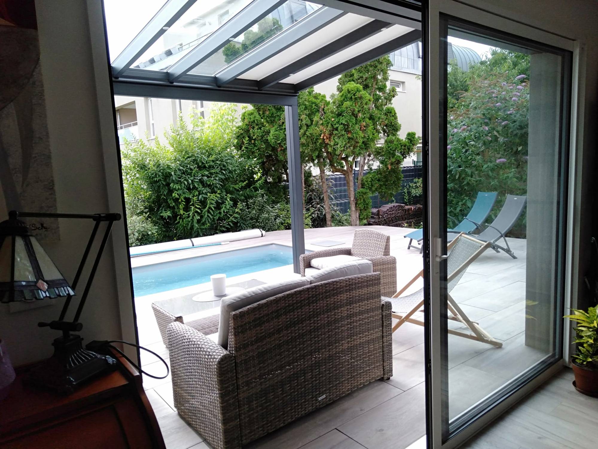 Pergola moderne en aluminium avec toit transparent offrant une vue piscine