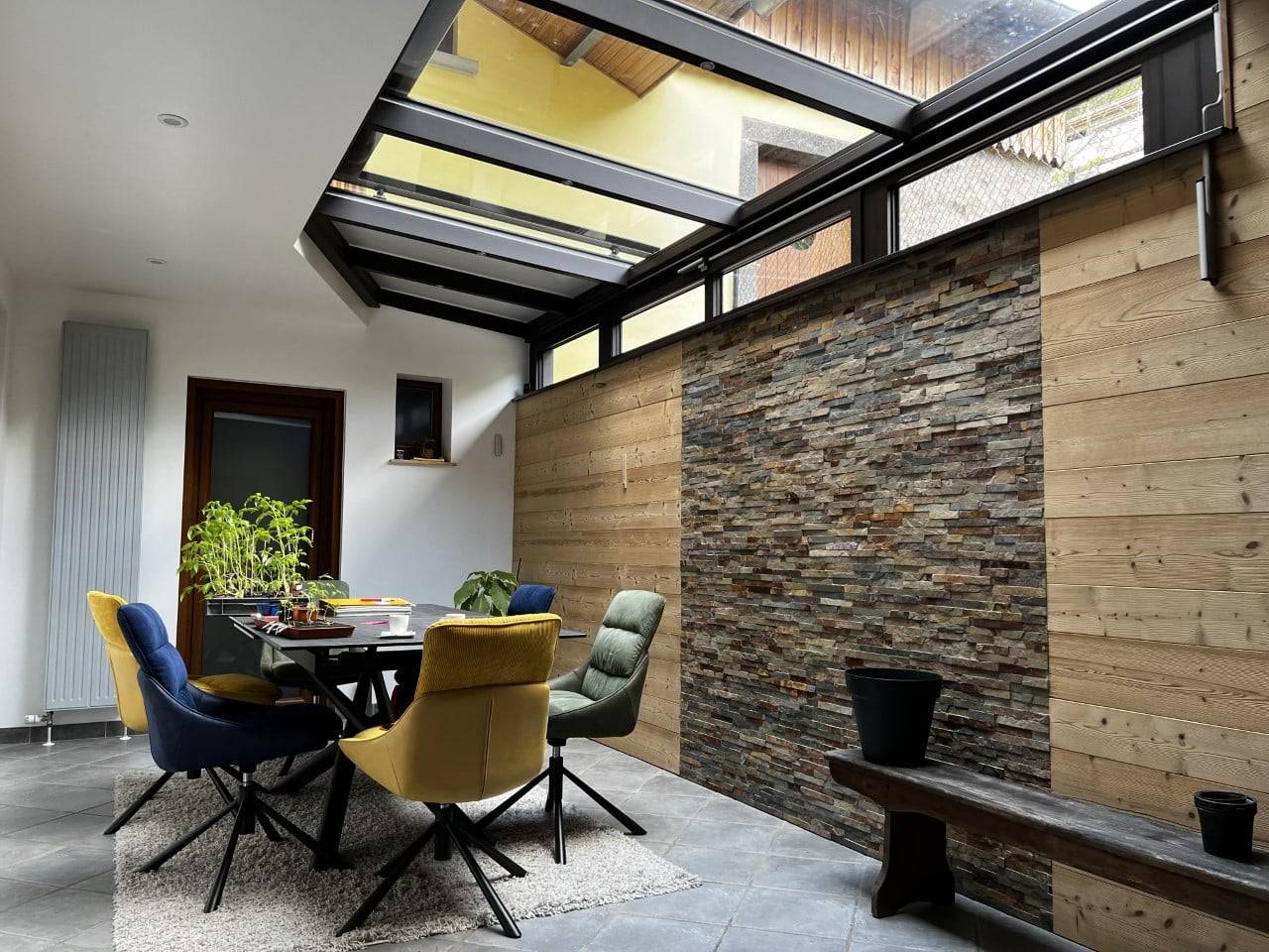 Véranda moderne avec toit en verre et mur en pierre naturelle