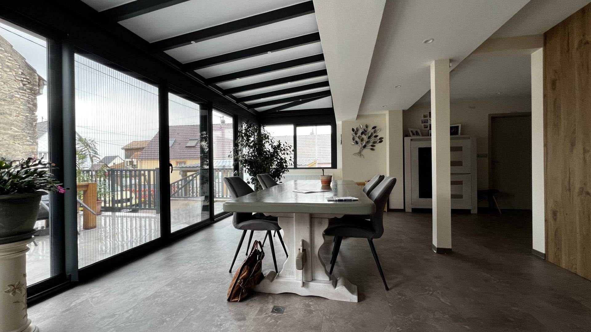 Véranda lumineuse avec vue extérieure et mobilier moderne